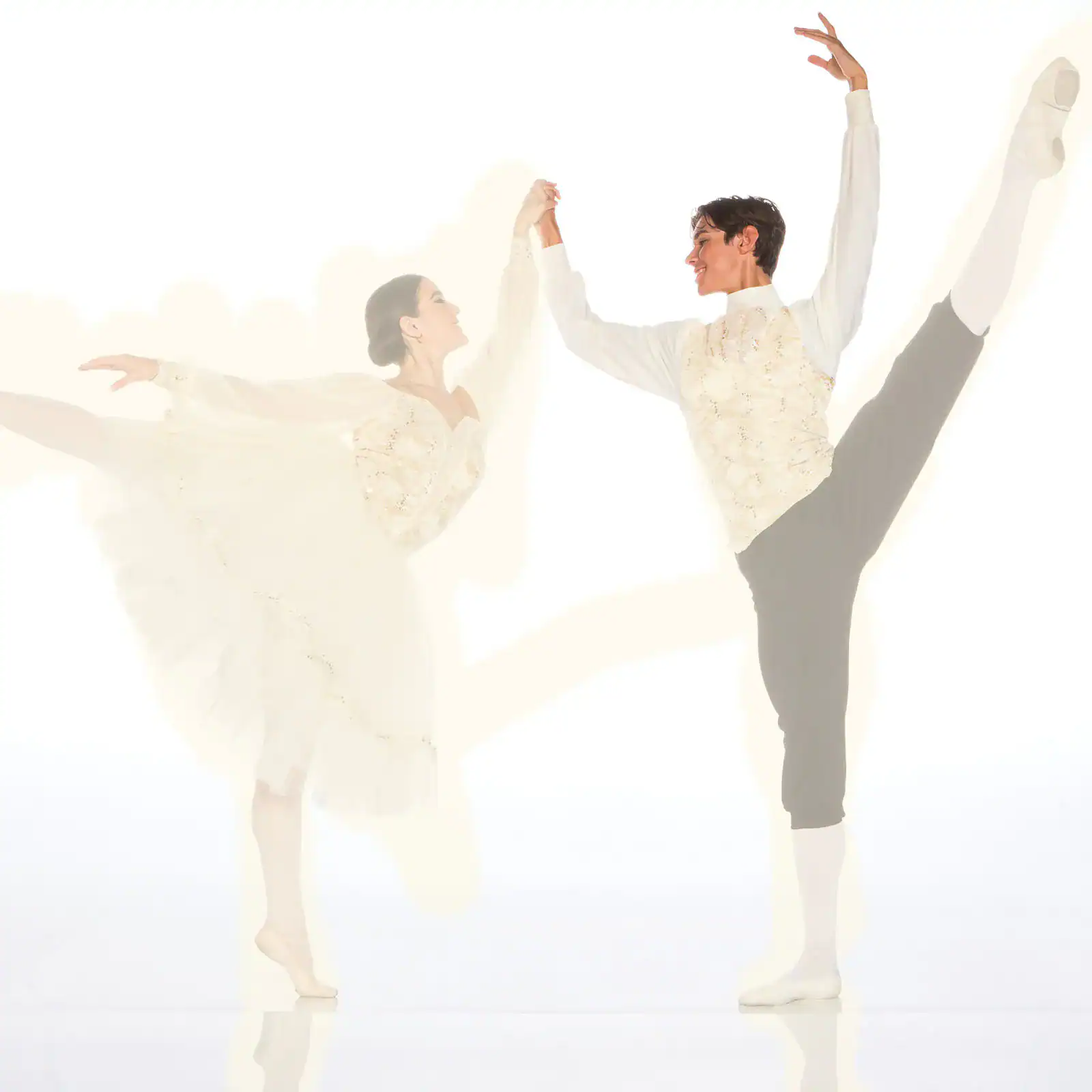 Ballet dancers performing elegant partnered high leg extensions