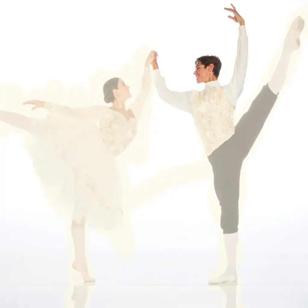 Two ballet dancers perform graceful partnered poses.