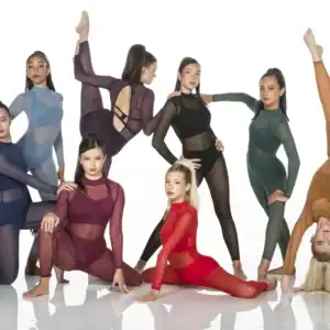 Seven dancers pose in colorful sheer leotards on white background.