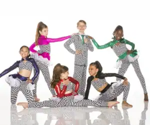 Six young dancers pose in colorful checkerboard costumes.
