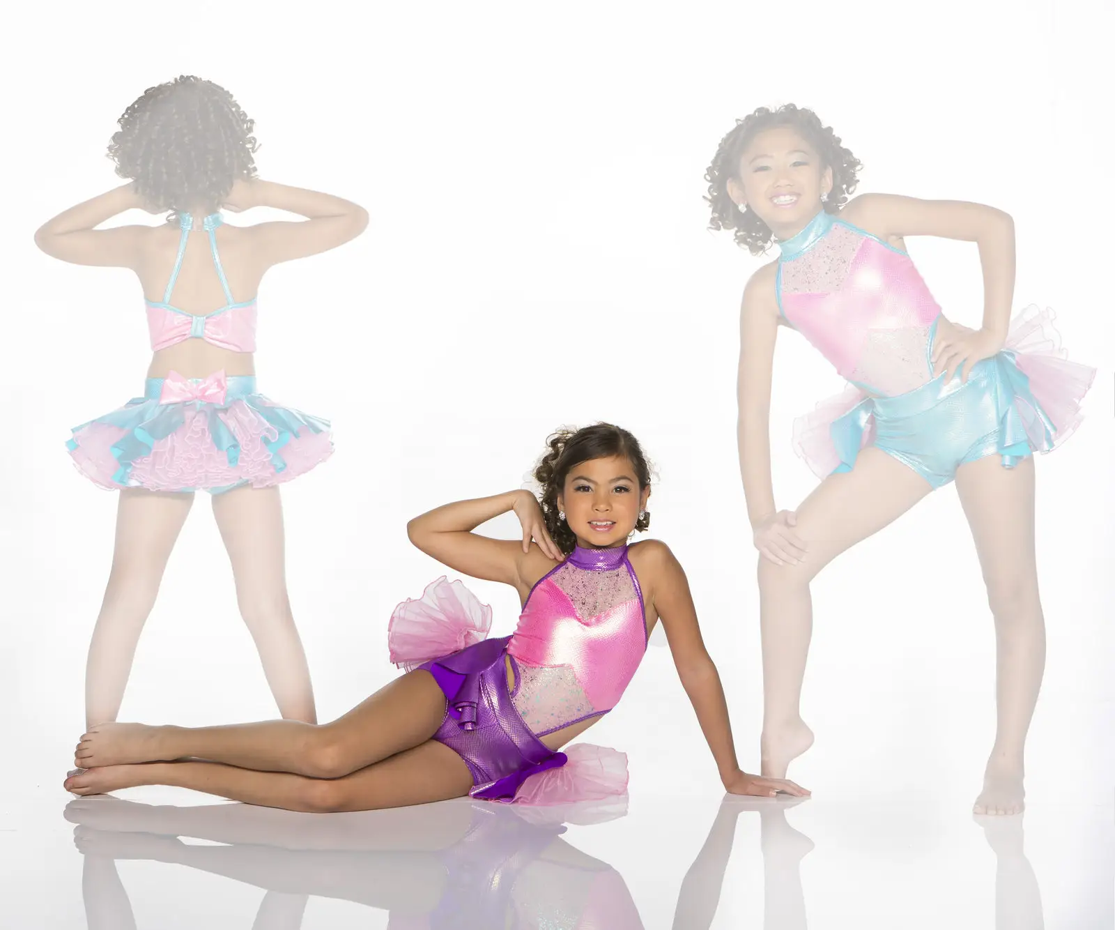 Three girls model colorful dance costumes against a white background.