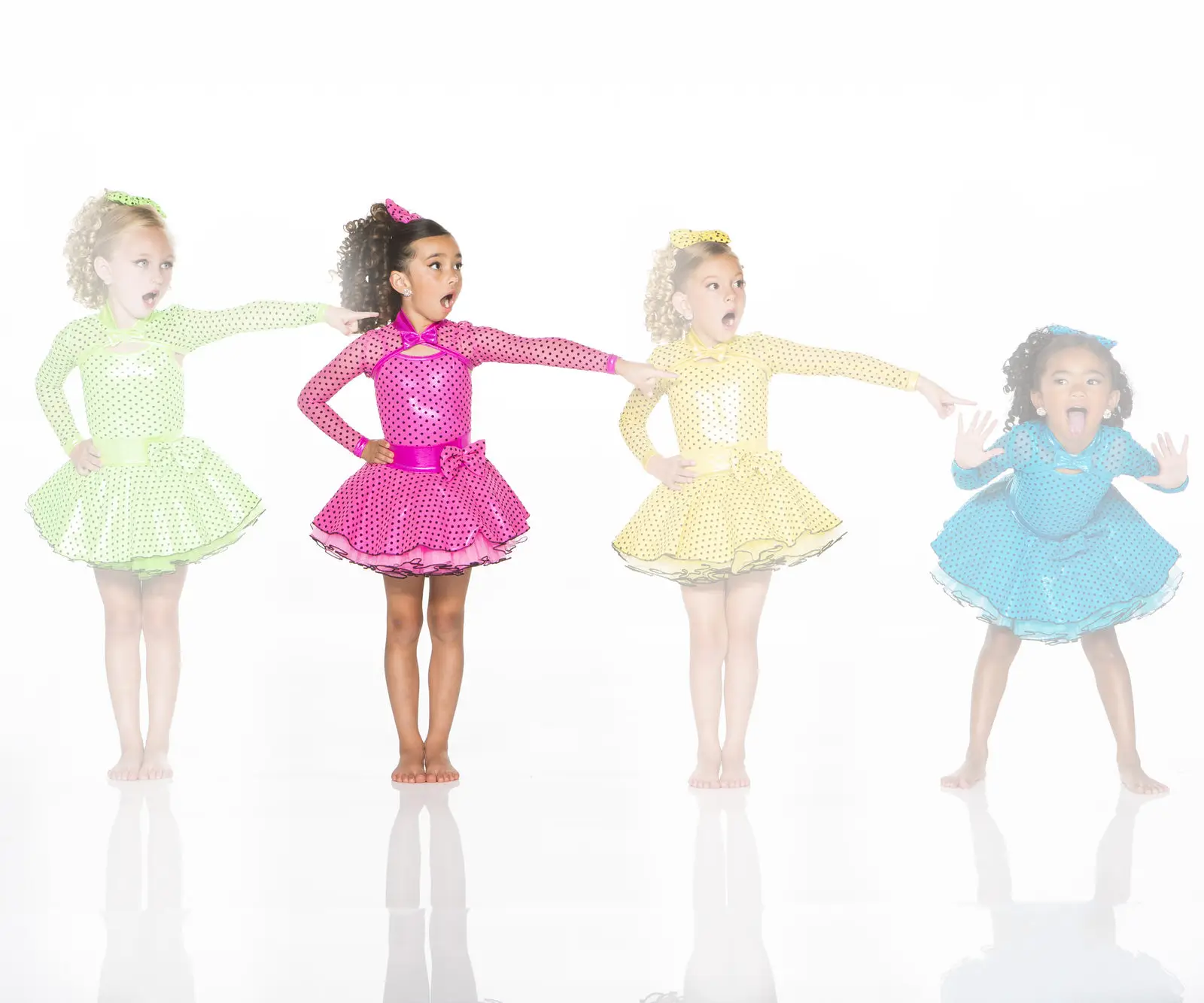 Four girls in colorful polka-dot dresses pointing playfully