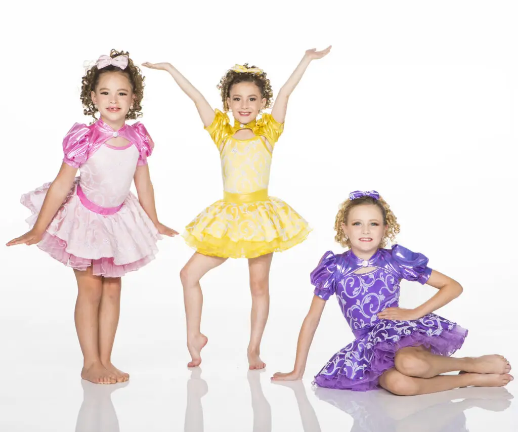Three young girls wearing colorful dance costumes posing