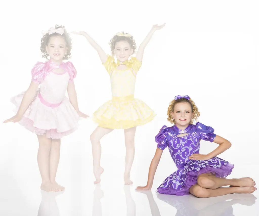 Three girls wearing colorful princess-style dance costumes