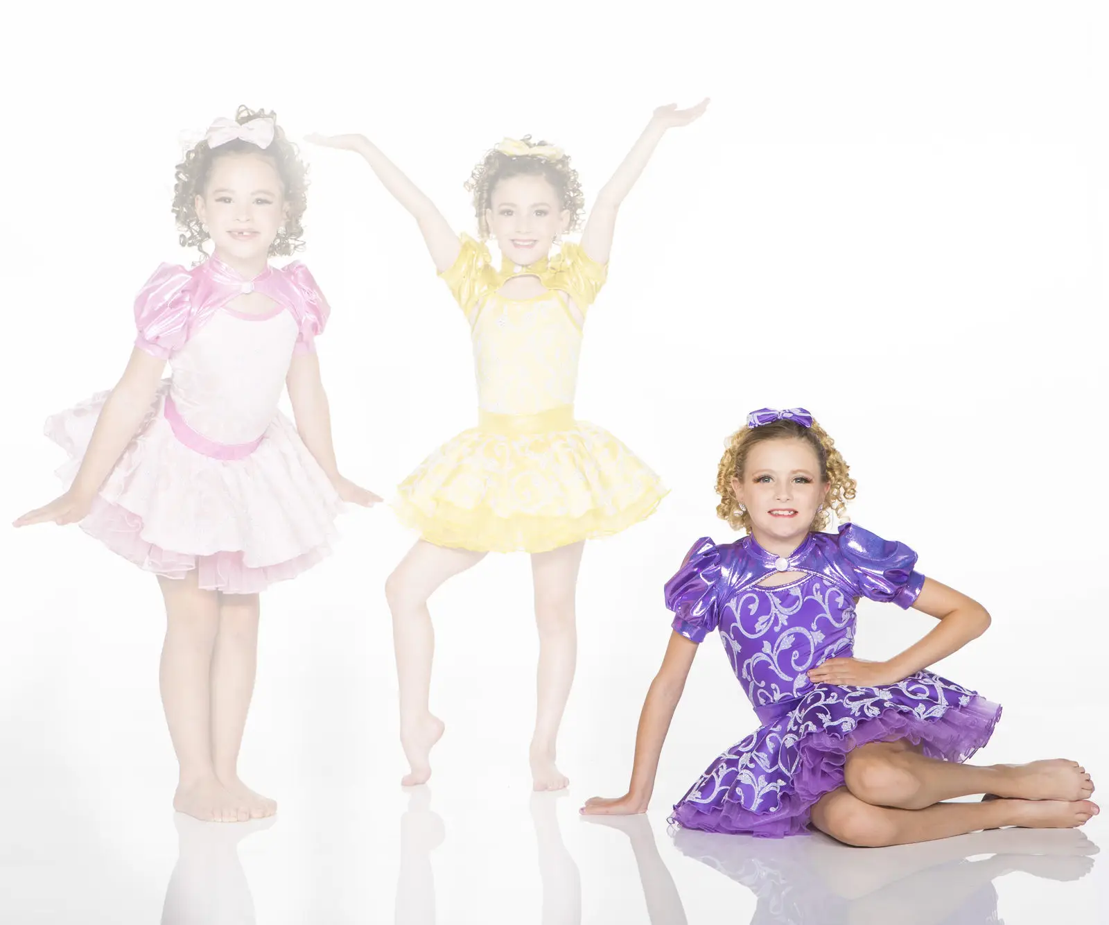 Three girls wearing colorful princess-style dance costumes