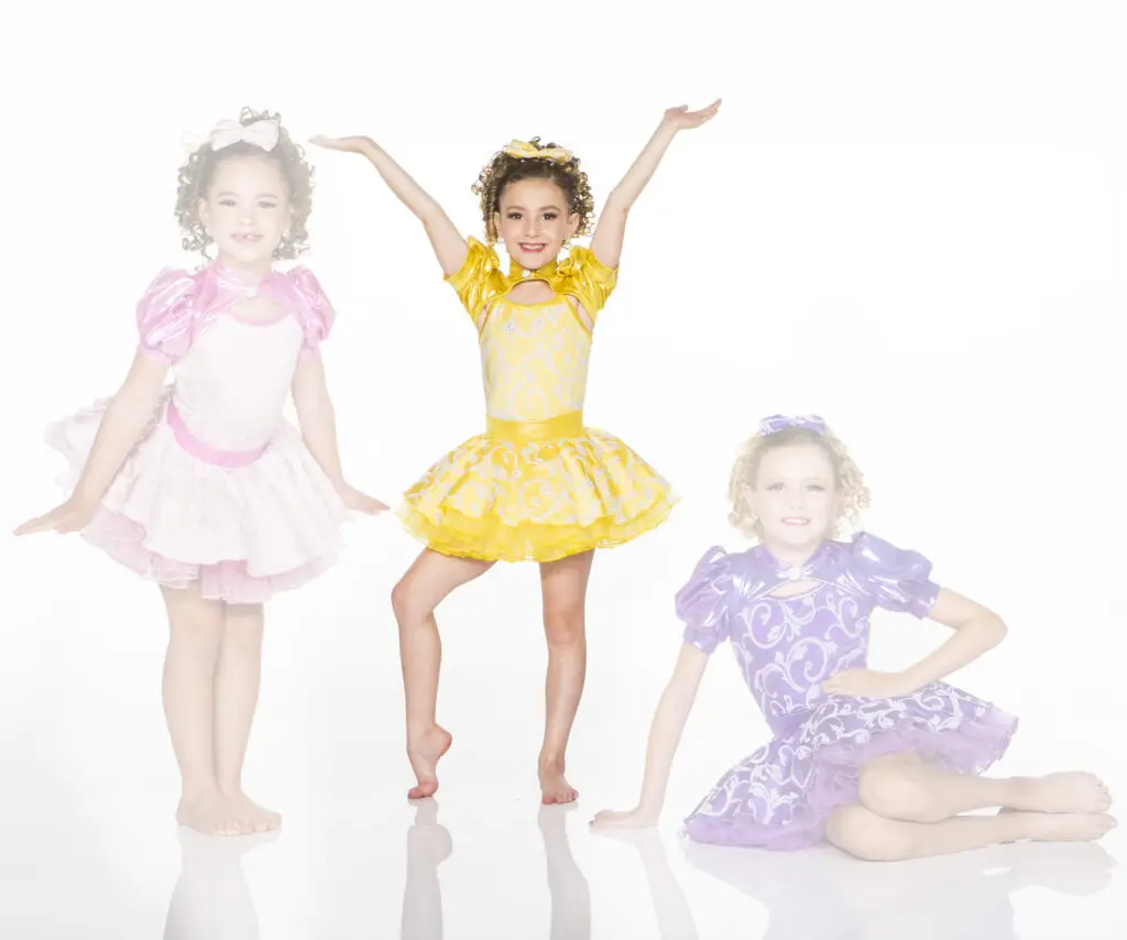 Three young dancers wearing colorful pink, yellow, and purple costumes