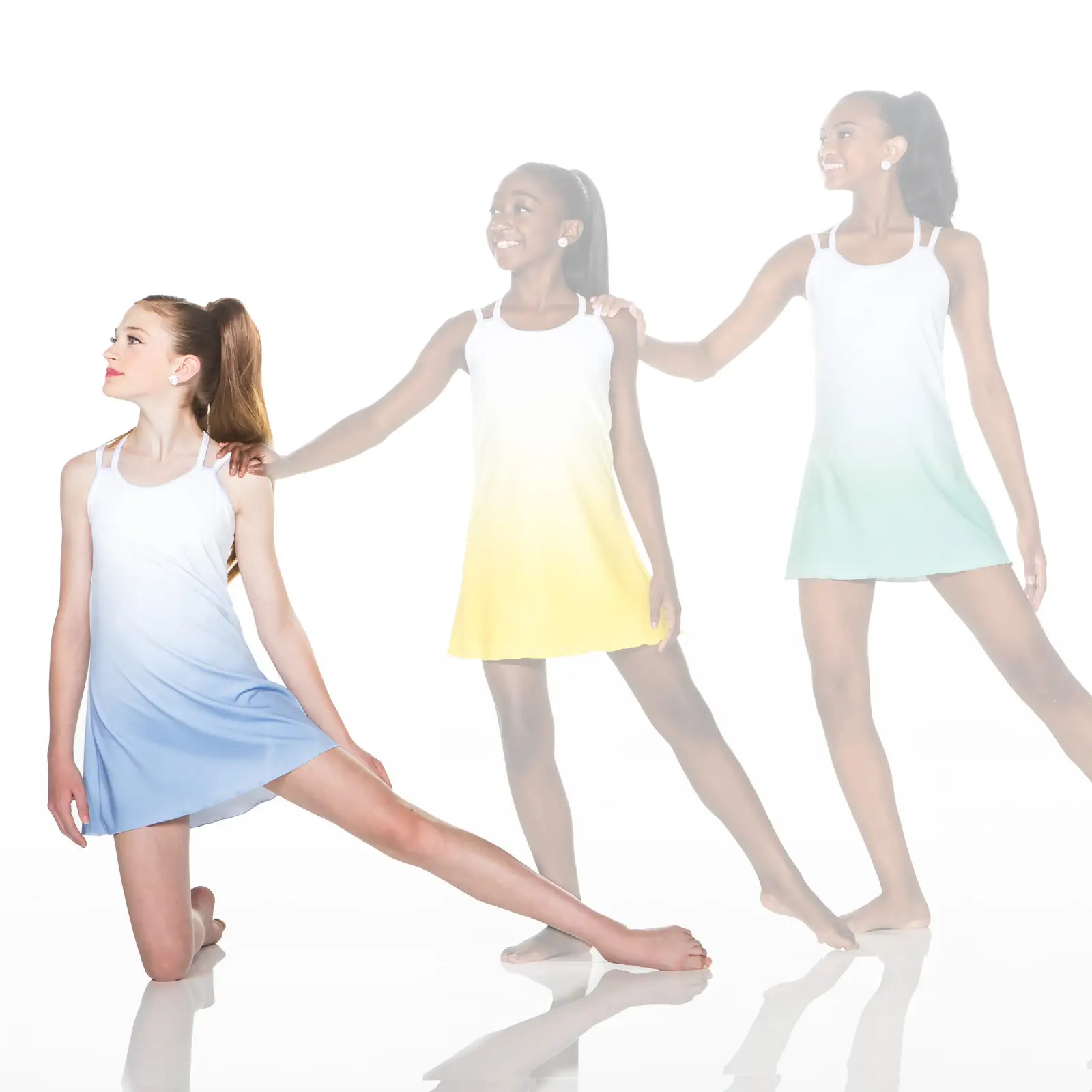 Three dancers in pastel dresses pose against a white background.