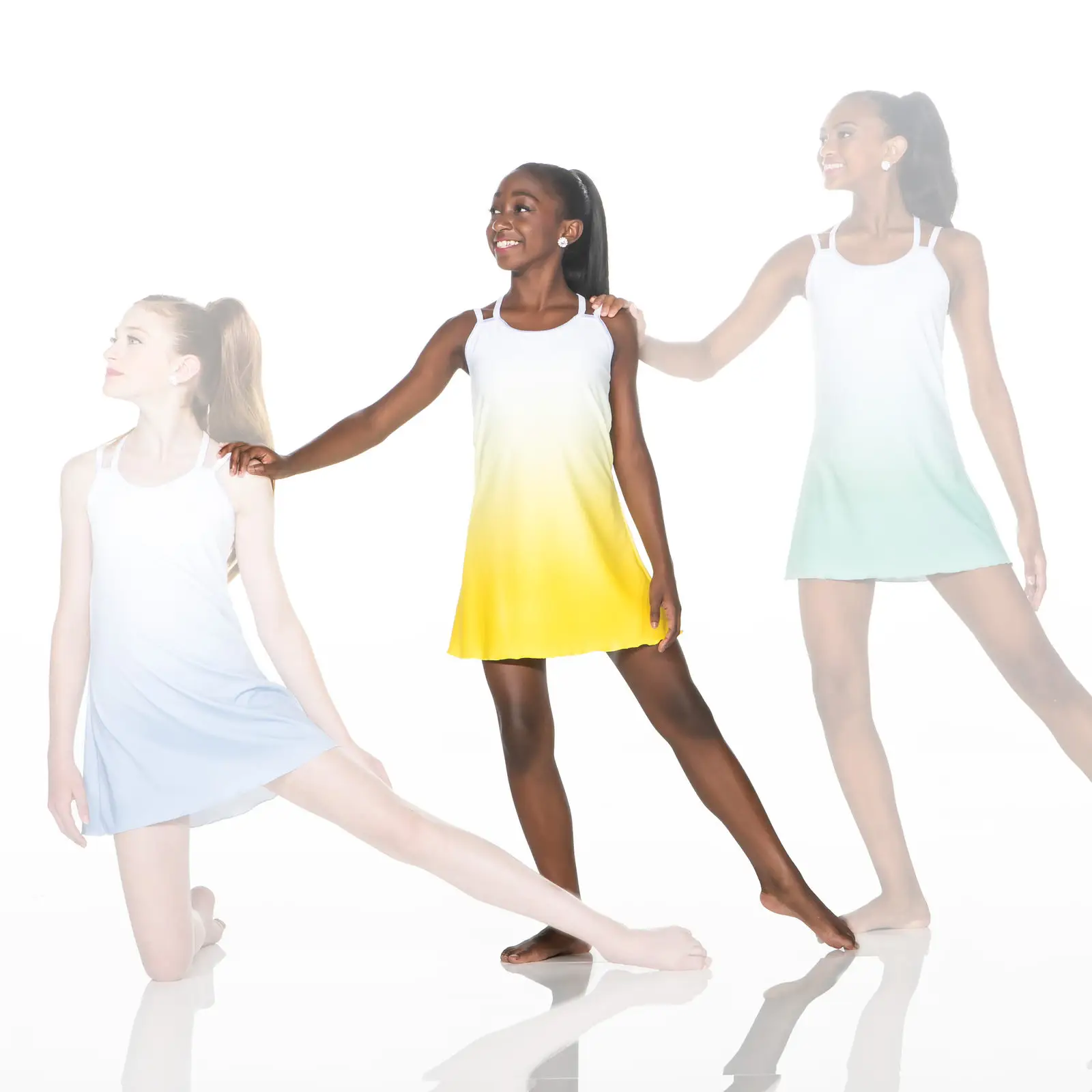Three dancers in pastel dresses pose against a white background.