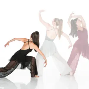Three contemporary dancers posing in flowing dresses on white background.