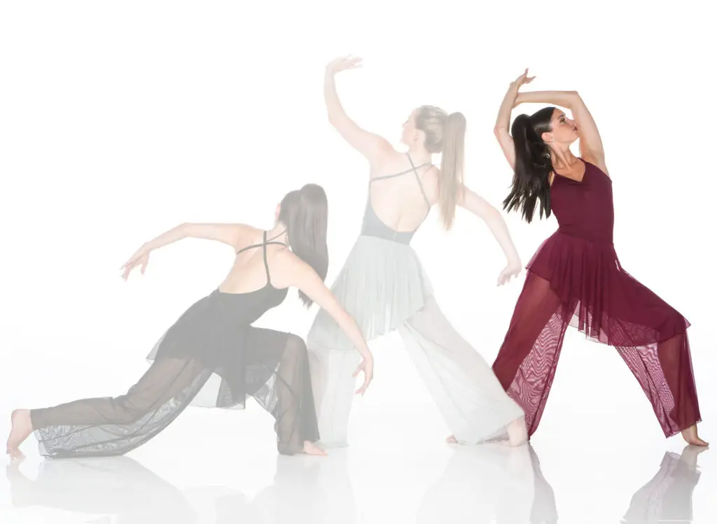 Three women in flowing dresses striking dance poses