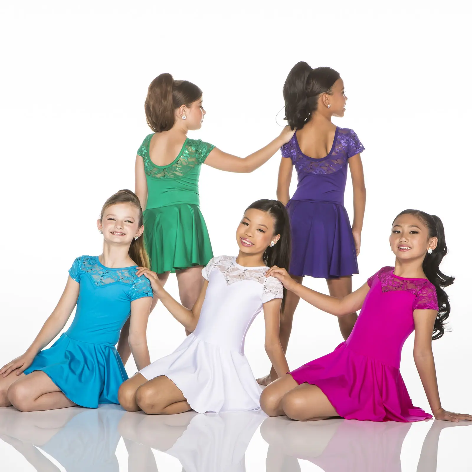 Five young dancers wearing colorful dresses pose in a studio.