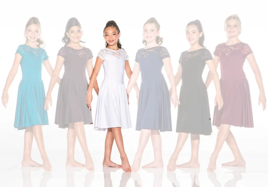 Six girls wearing lace dresses, central dancer highlighted