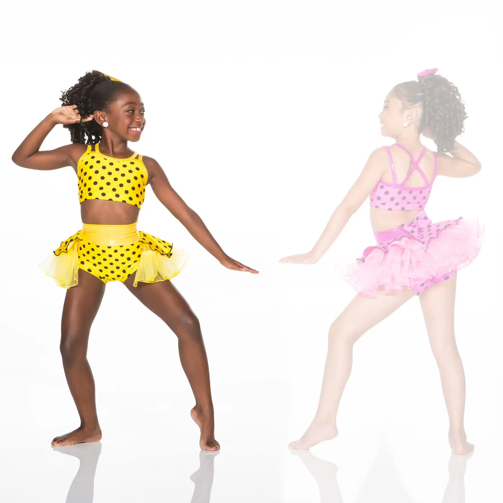 Two young dancers in colorful polka-dot costumes posing