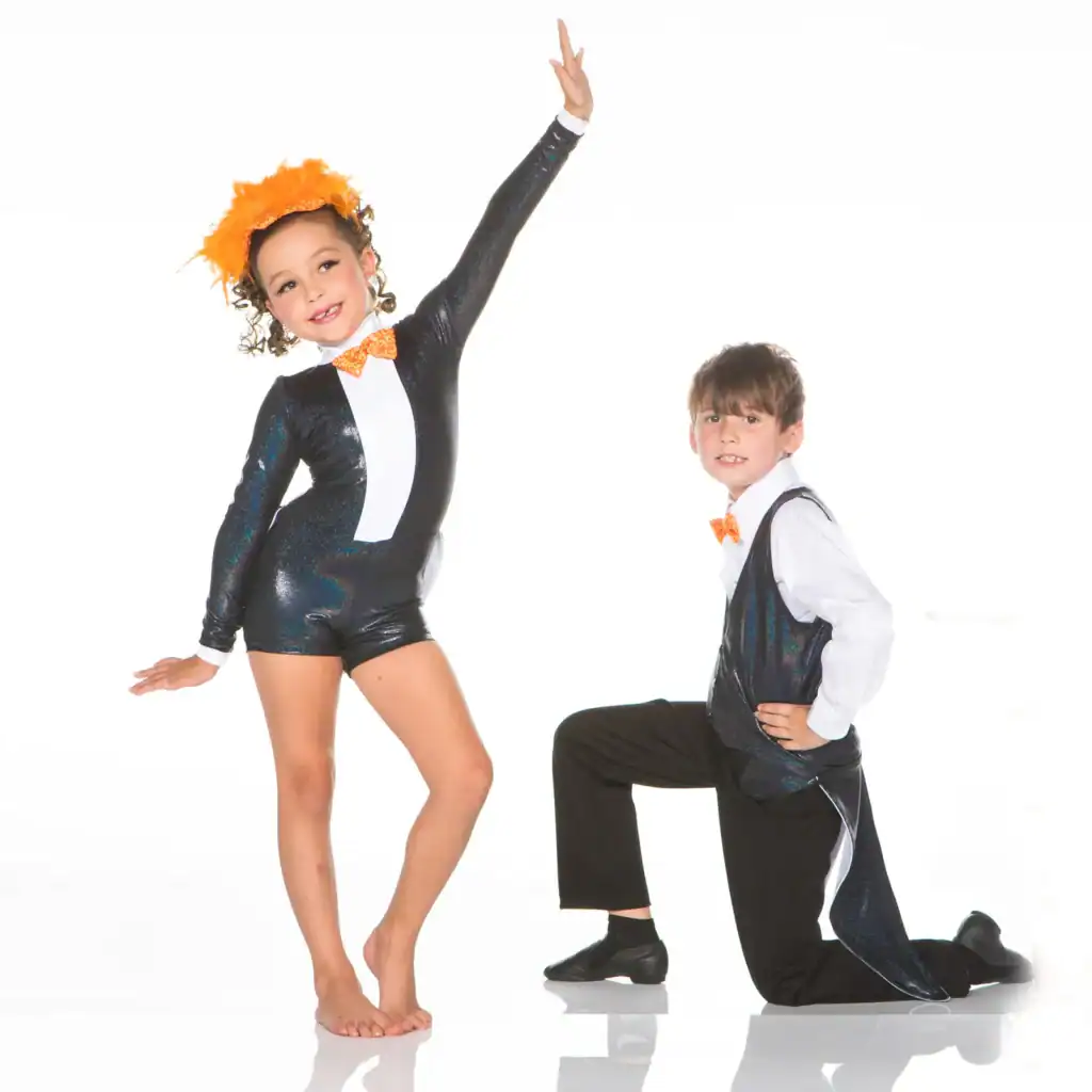 Two children in glittery dance costumes pose on white background.