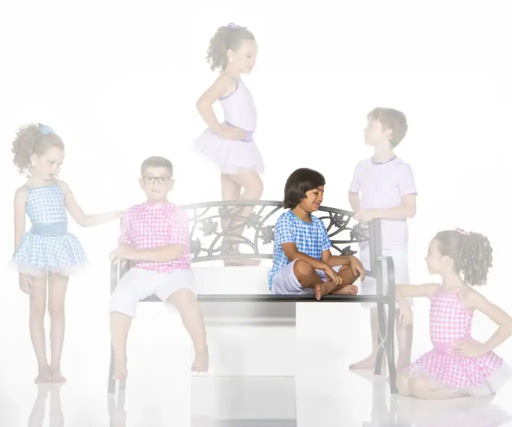 Six children in gingham outfits pose around a decorative bench.