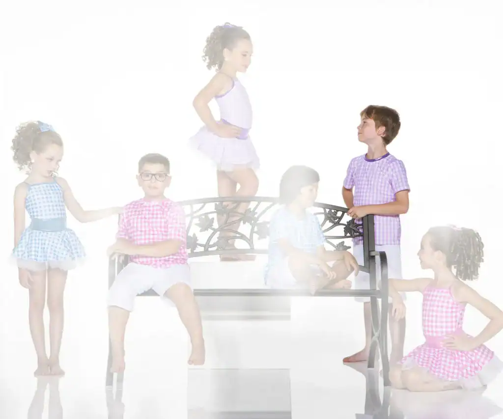 Children in colorful gingham outfits pose around a decorative bench.