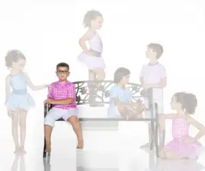 Children in colorful gingham outfits around a decorative bench