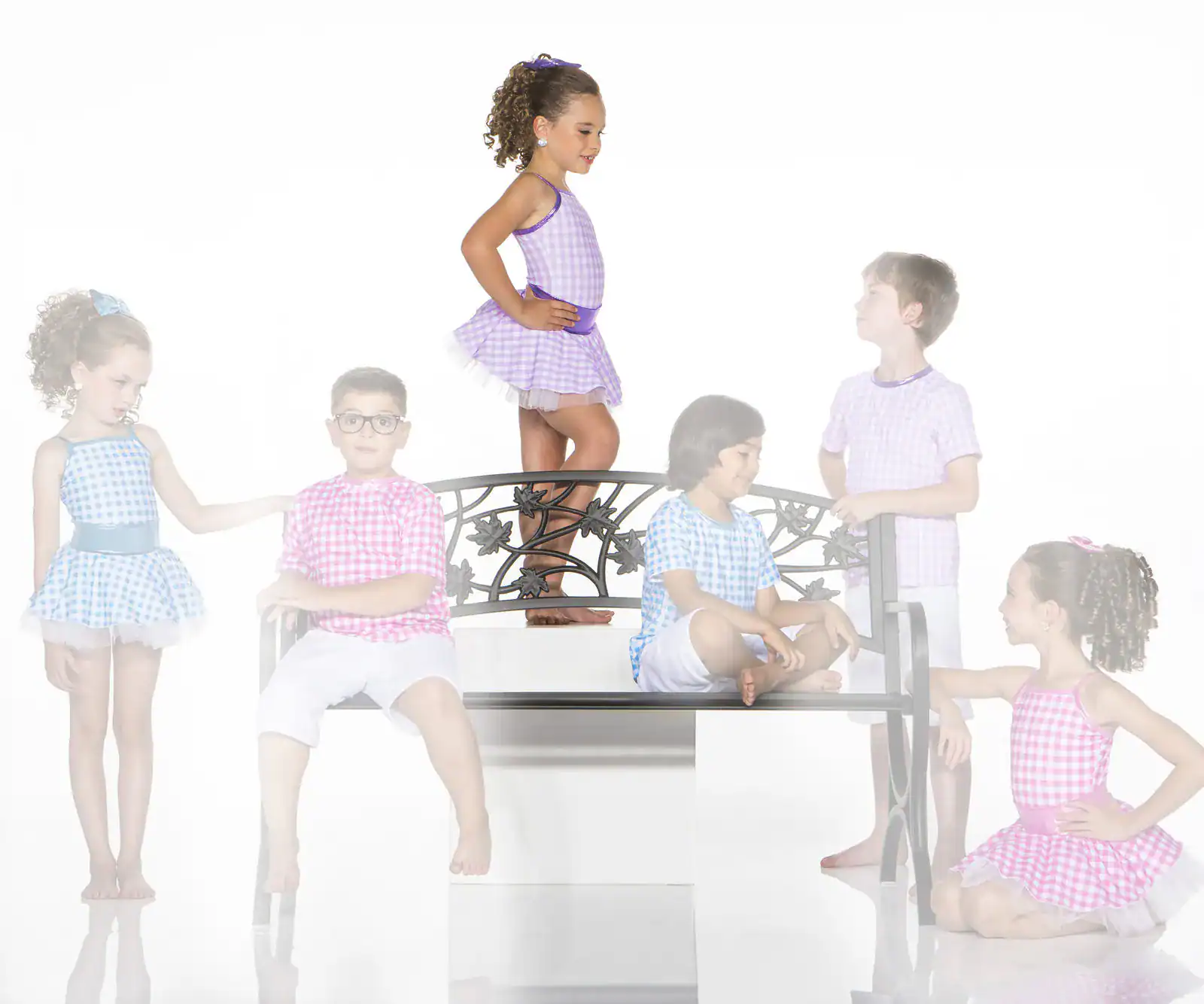 Children in colorful gingham outfits pose around decorative bench
