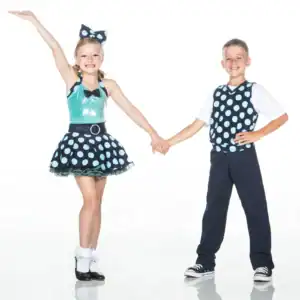 Two children holding hands in matching polka-dot dance costumes.