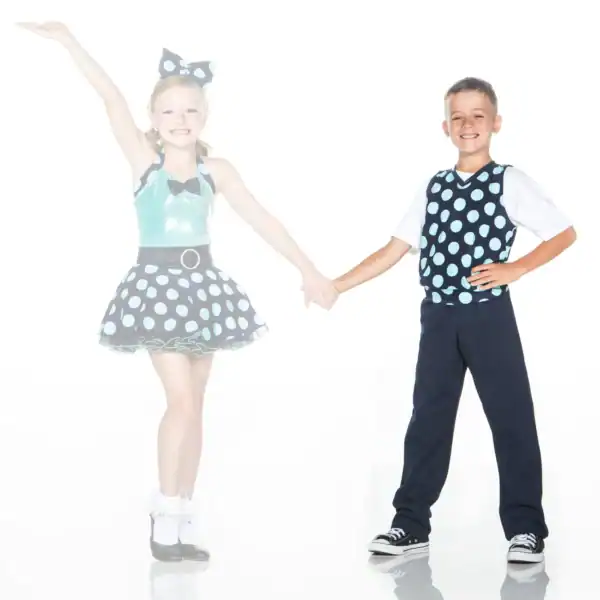 Two children holding hands in matching polka-dot dance costumes.