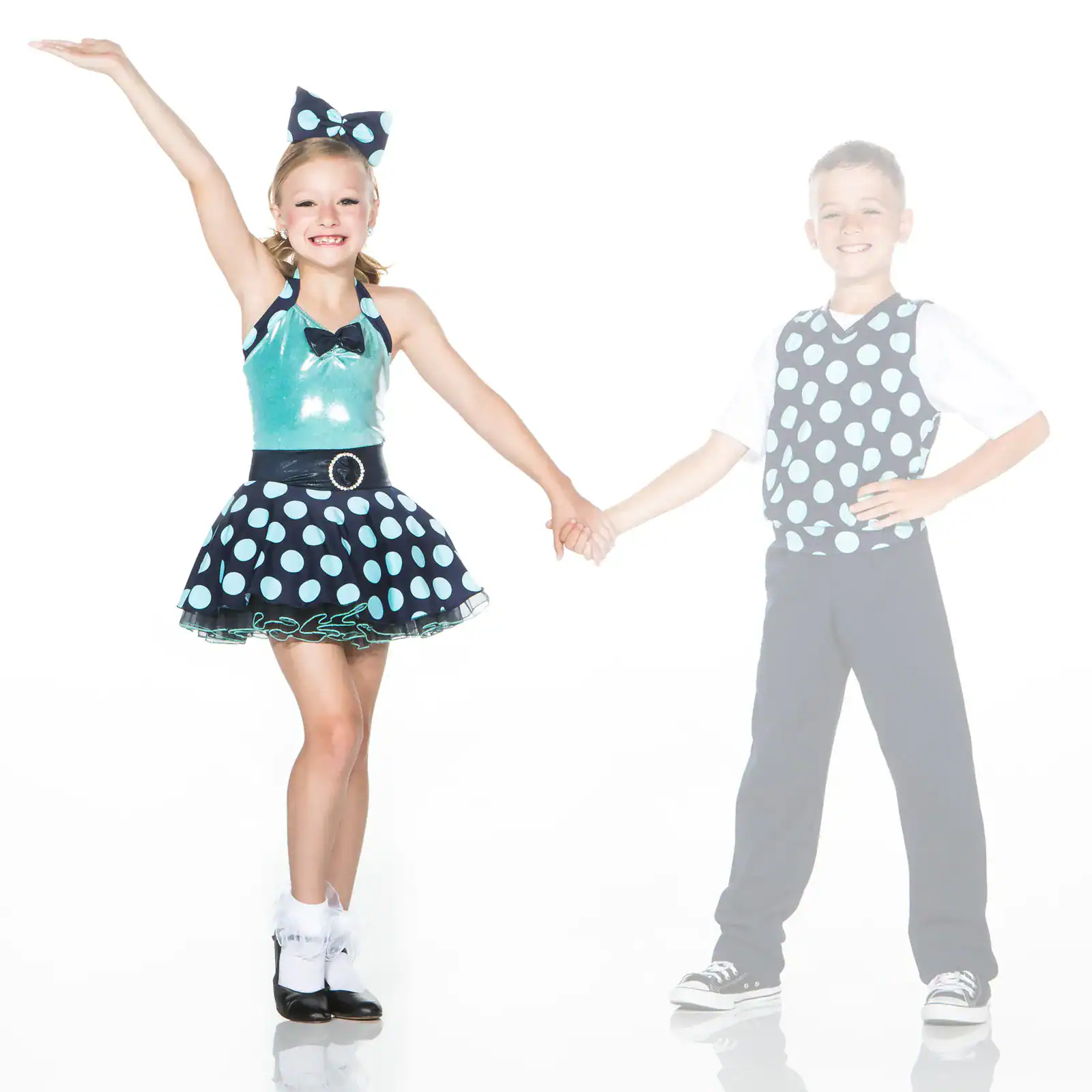 Two children in matching polka-dot dance costumes holding hands