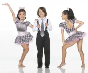Three children modeling coordinated houndstooth dance costumes.