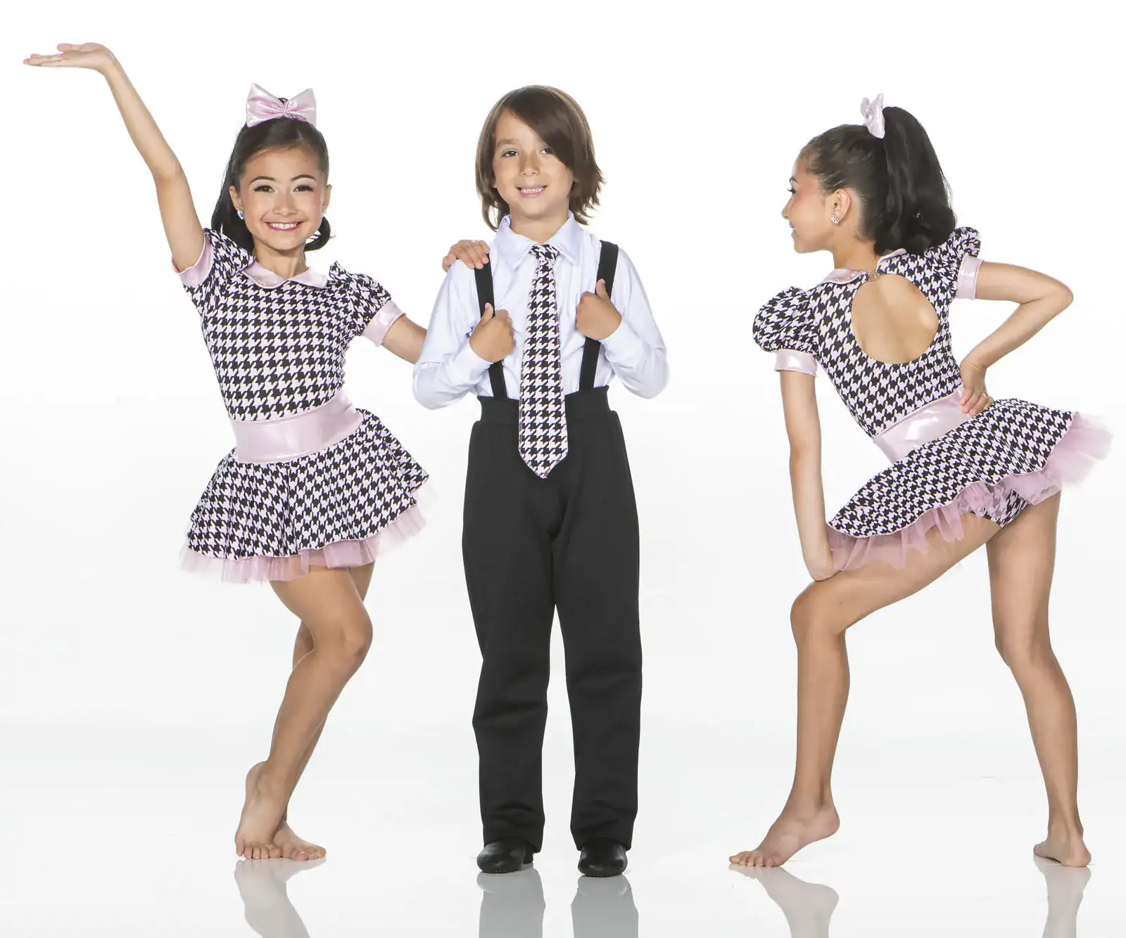 Three children modeling coordinated houndstooth dance costumes.