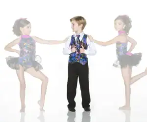 Three children in colorful dance costumes pose together.
