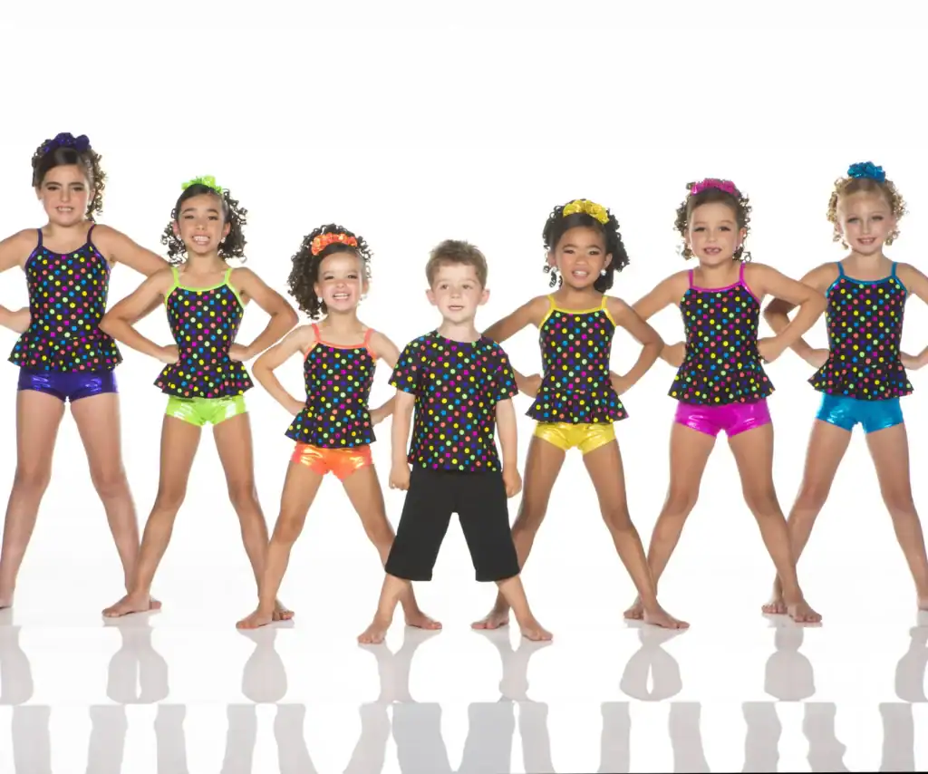 Seven children wearing colorful polka-dot dance costumes pose together.