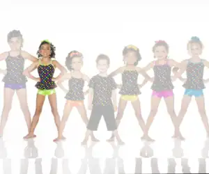 Seven children in colorful polka-dot dance costumes posing together