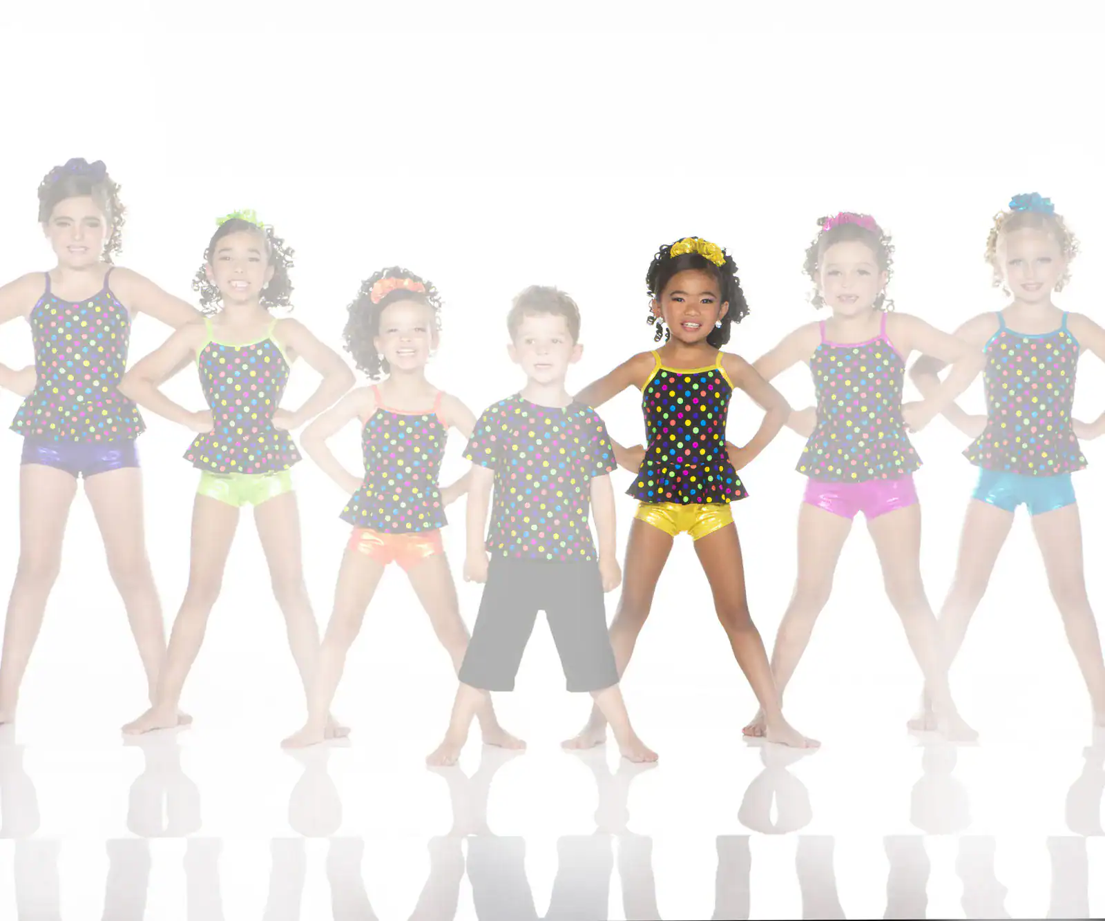 Seven children pose in colorful polka-dot dance outfits.