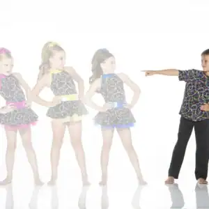 Boy points toward three girls in colorful dance costumes.
