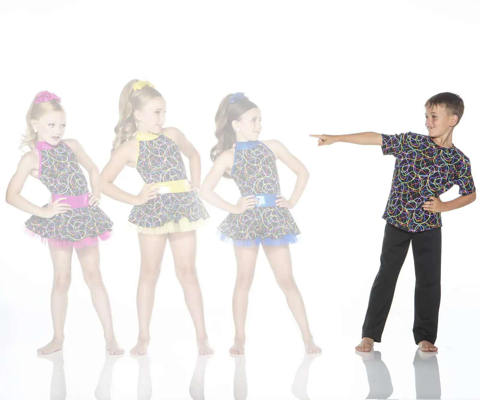 Boy points toward three girls in colorful dance costumes.