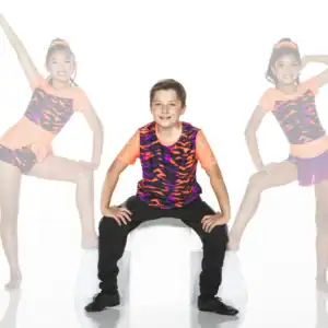 Boy seated between two young dancers in colorful costumes