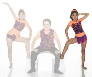 Three young dancers posing in colorful orange and patterned costumes