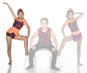 Three young dancers posing in colorful costumes against white background.