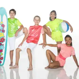 Four children pose with surfboard and beach ball.