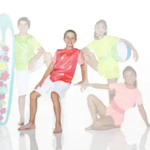 Four children in colorful beachwear pose with surfboard and ball.