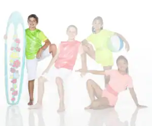 Four children pose with surfboard and beach ball.