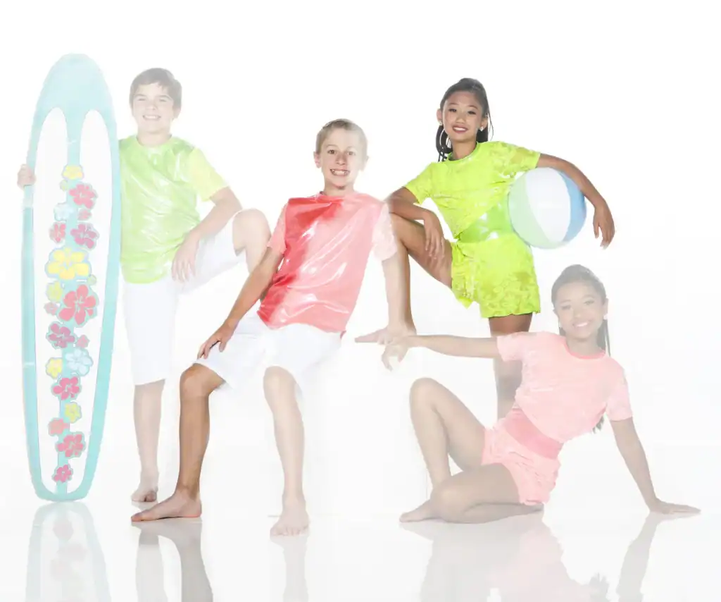 Four children pose with surfboard and beach ball