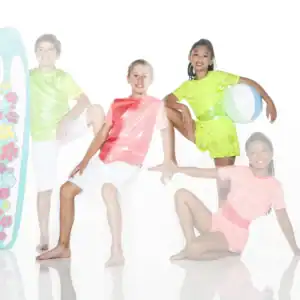 Four children pose with surfboard and beach ball