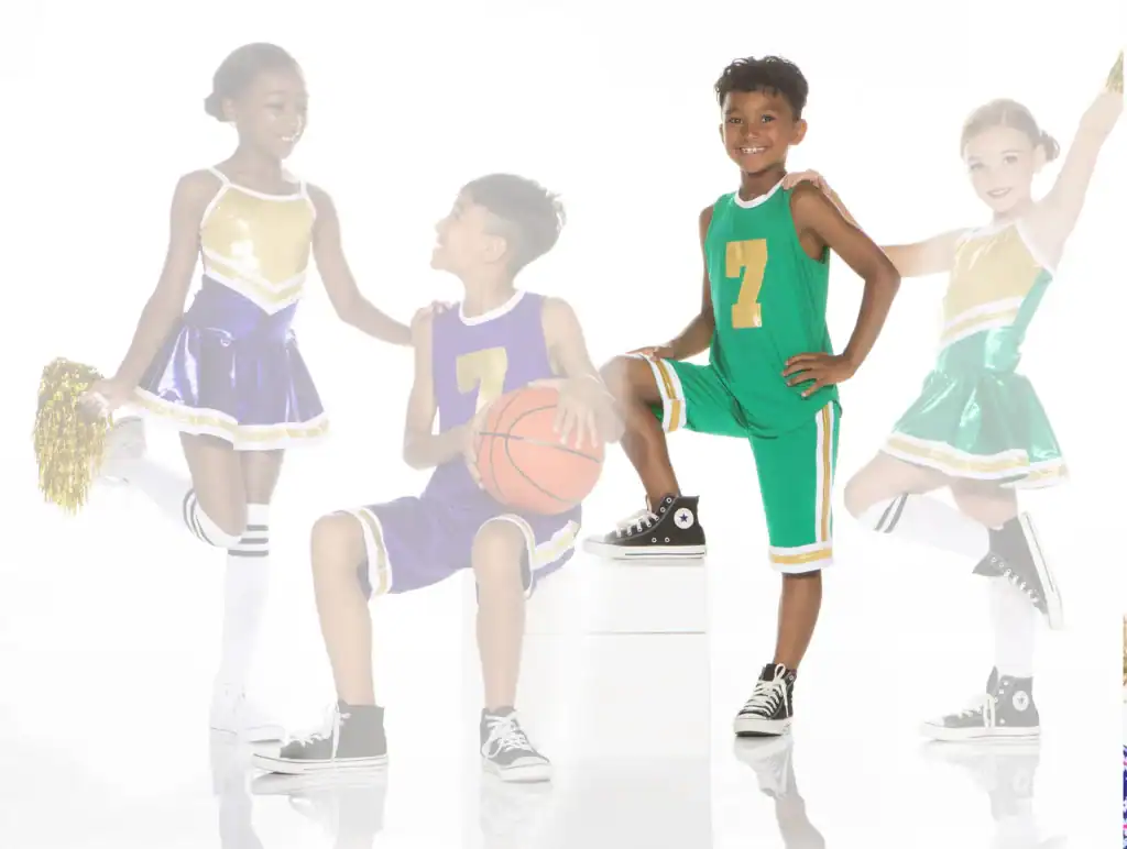 Children in basketball uniforms and cheerleading outfits posing together
