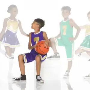 Children in basketball uniforms and cheerleading outfits pose together