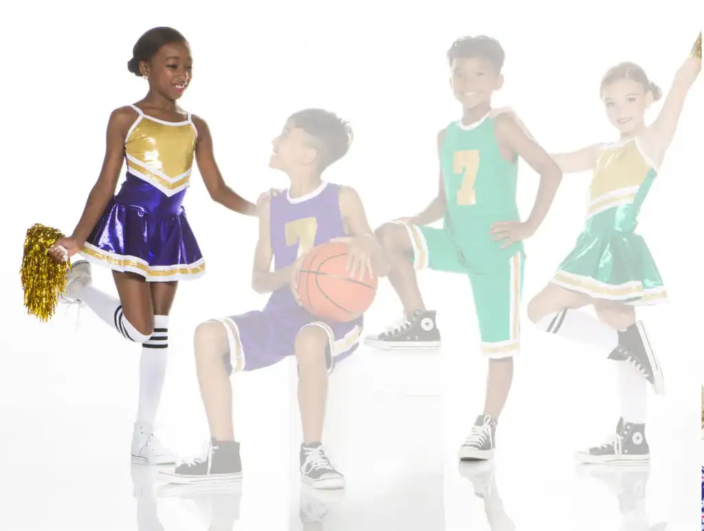 Four children in cheerleading and basketball uniforms posing together