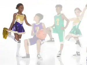 Four children in cheerleading and basketball uniforms posing together