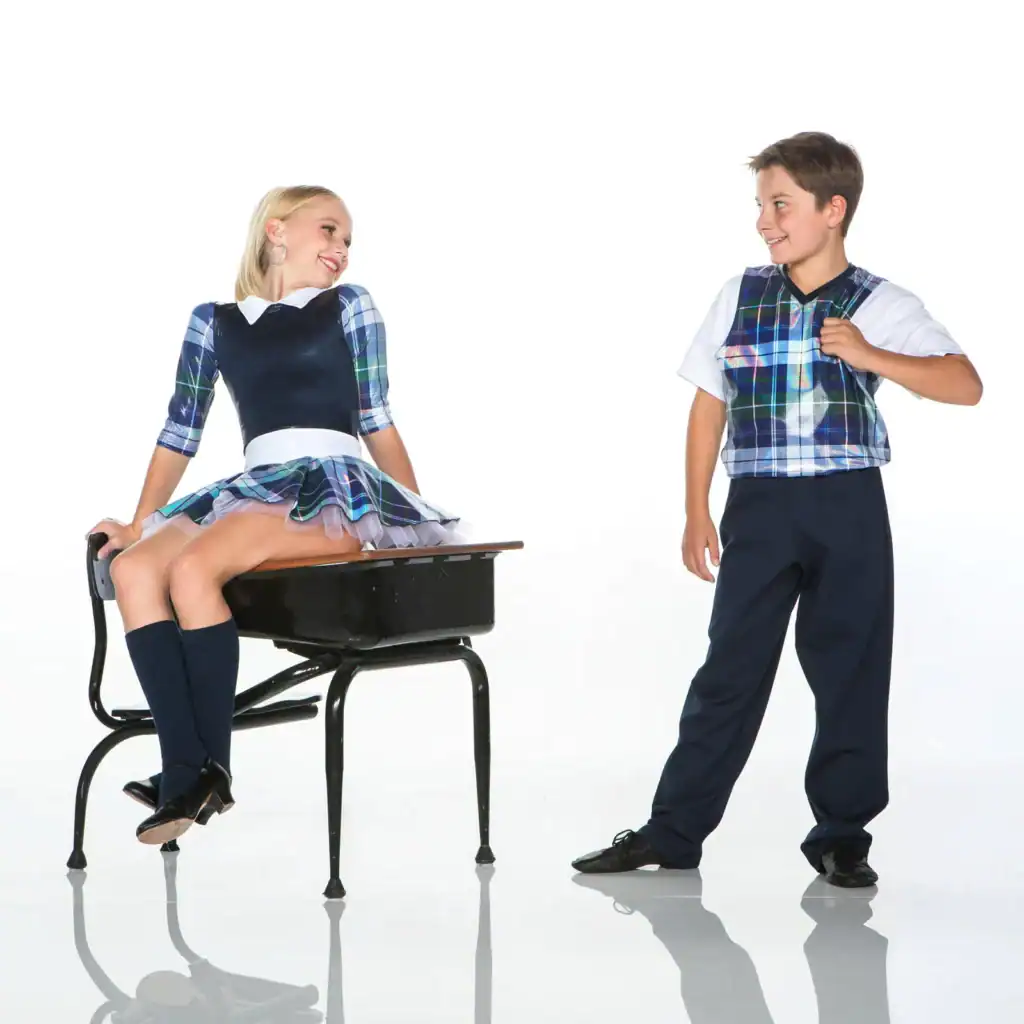 Two children wearing matching plaid school uniforms smile together.