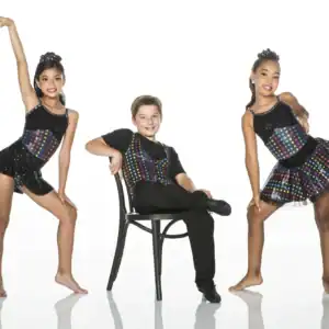 Three young dancers wearing colorful polka-dot costumes pose in studio.