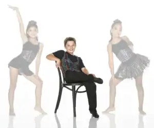 Three young dancers in colorful costumes posing in studio