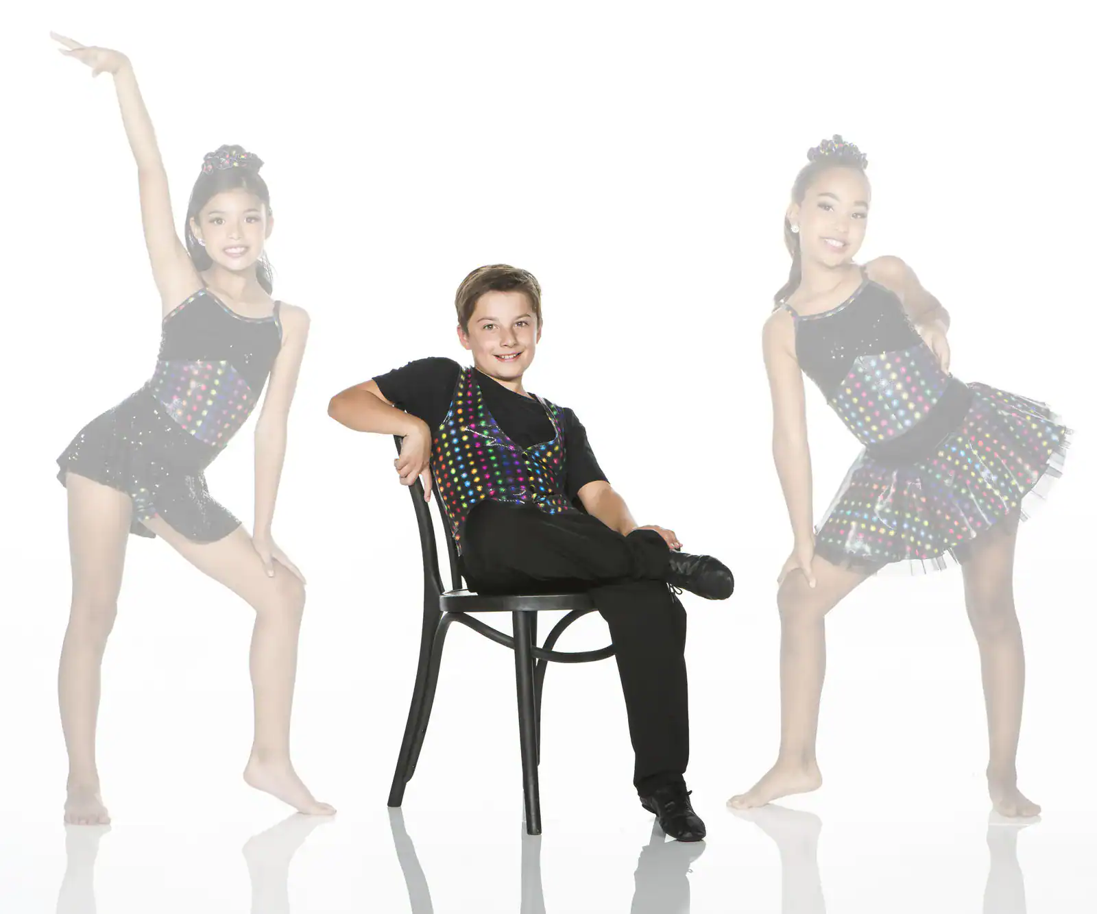 Three young dancers in colorful costumes posing in studio
