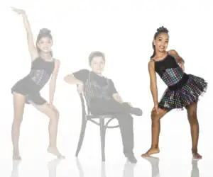Three young dancers in colorful polka-dot costumes posing